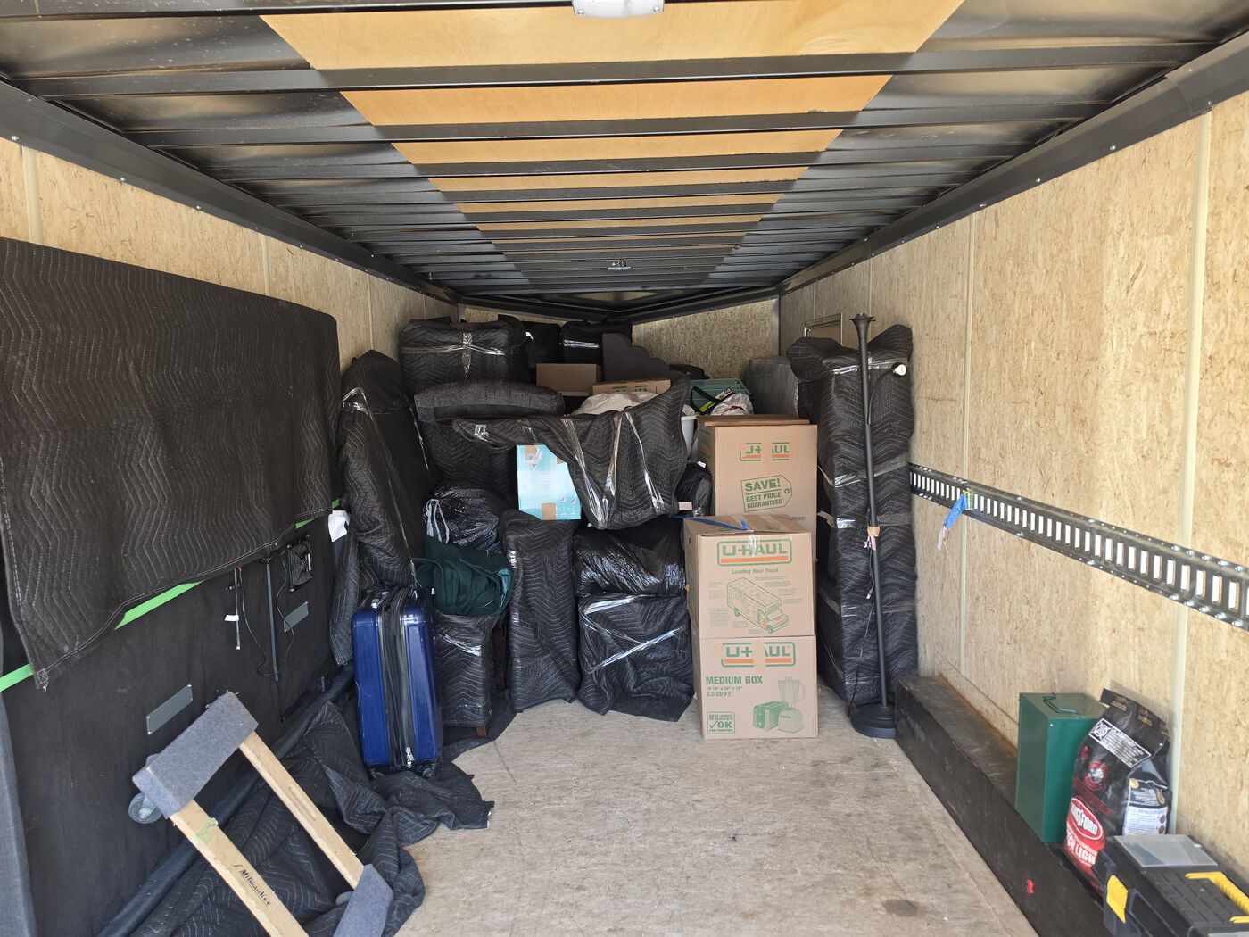 Moving trailer packed with blanket-wrapped furniture and boxes, ready for a long-distance move